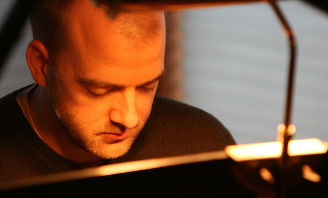Curt playing the piano, reflected in its polished surface
